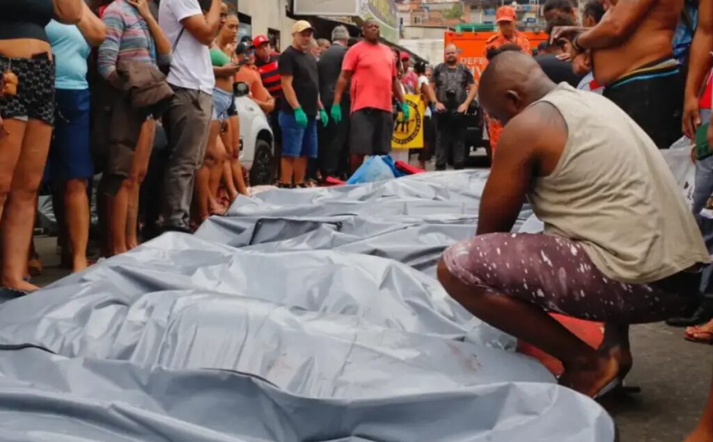 Cena da Operação Contenção no Rio de Janeiro com presença de vítimas em área urbana, moradores reunidos e clima de tensão após ação policial.