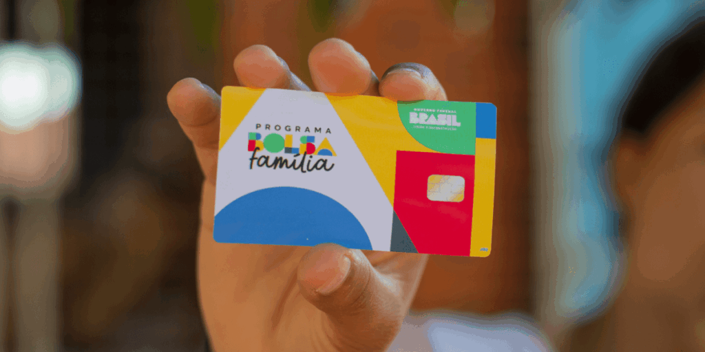 Cartão do Bolsa Família sendo segurado por beneficiária do programa social.