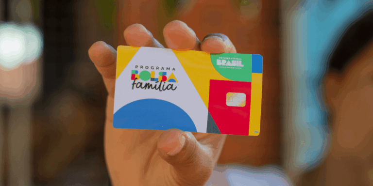 Cartão do Bolsa Família sendo segurado por beneficiária do programa social.