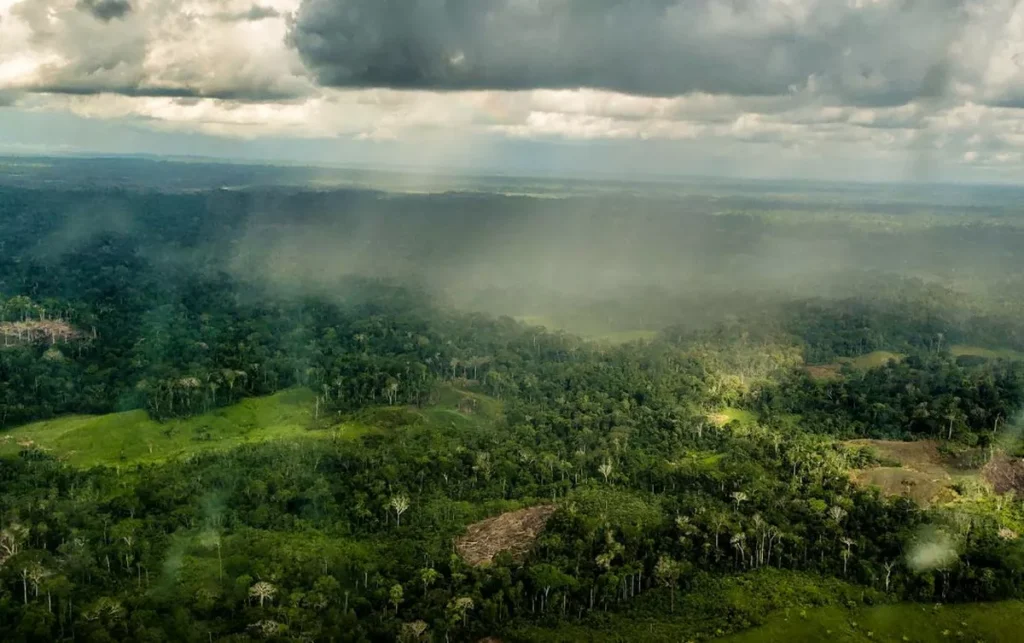 Céu com sol entre nuvens e pancadas de chuva, representando tempo instável e abafado na região amazônica.