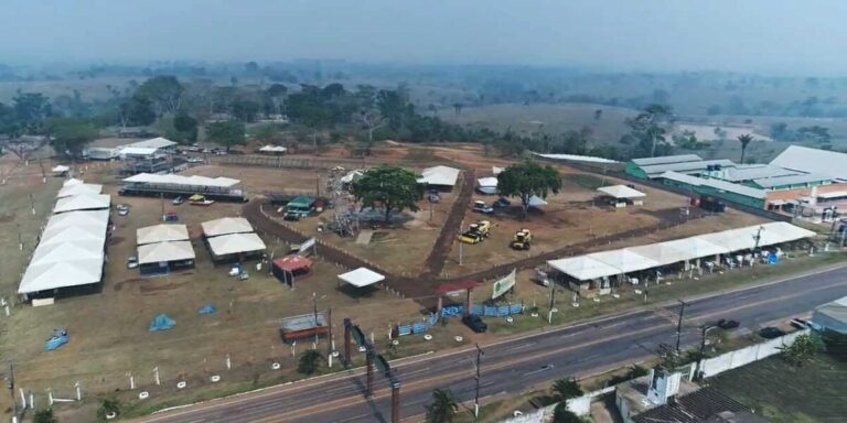 Público em feira agropecuária durante a ExpoQuinari em Senador Guiomard, com estandes, movimentação de visitantes e ambiente de exposição rural e cultural.
