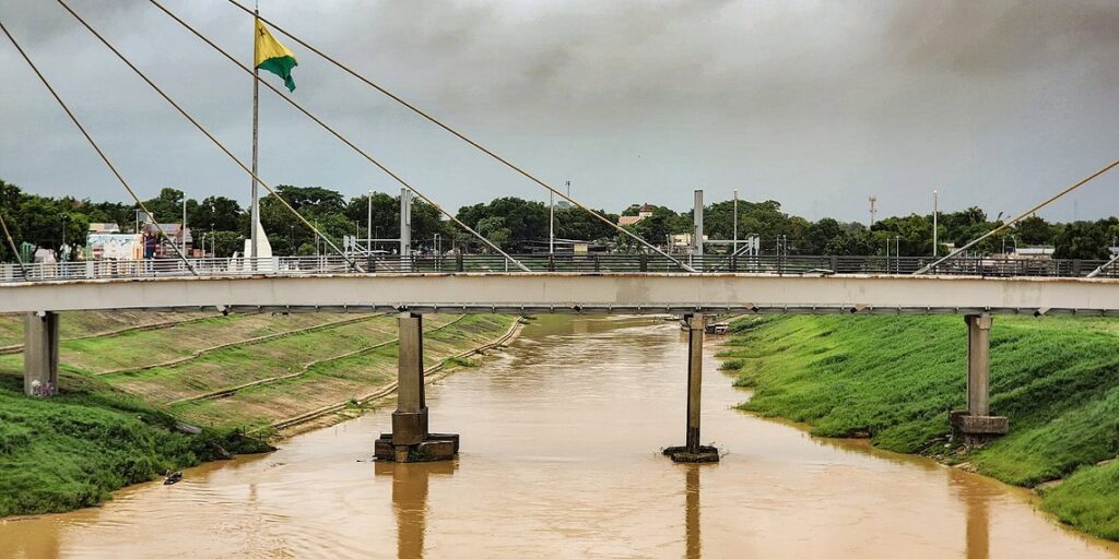 Extenso banco de areia exposto no meio do leito baixo do Rio Acre sob céu aberto durante período de forte estiagem.