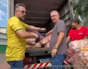 Alan Rick ajuda trabalhadores a carregar fardos em caminhão na Baixada da Sobral.
