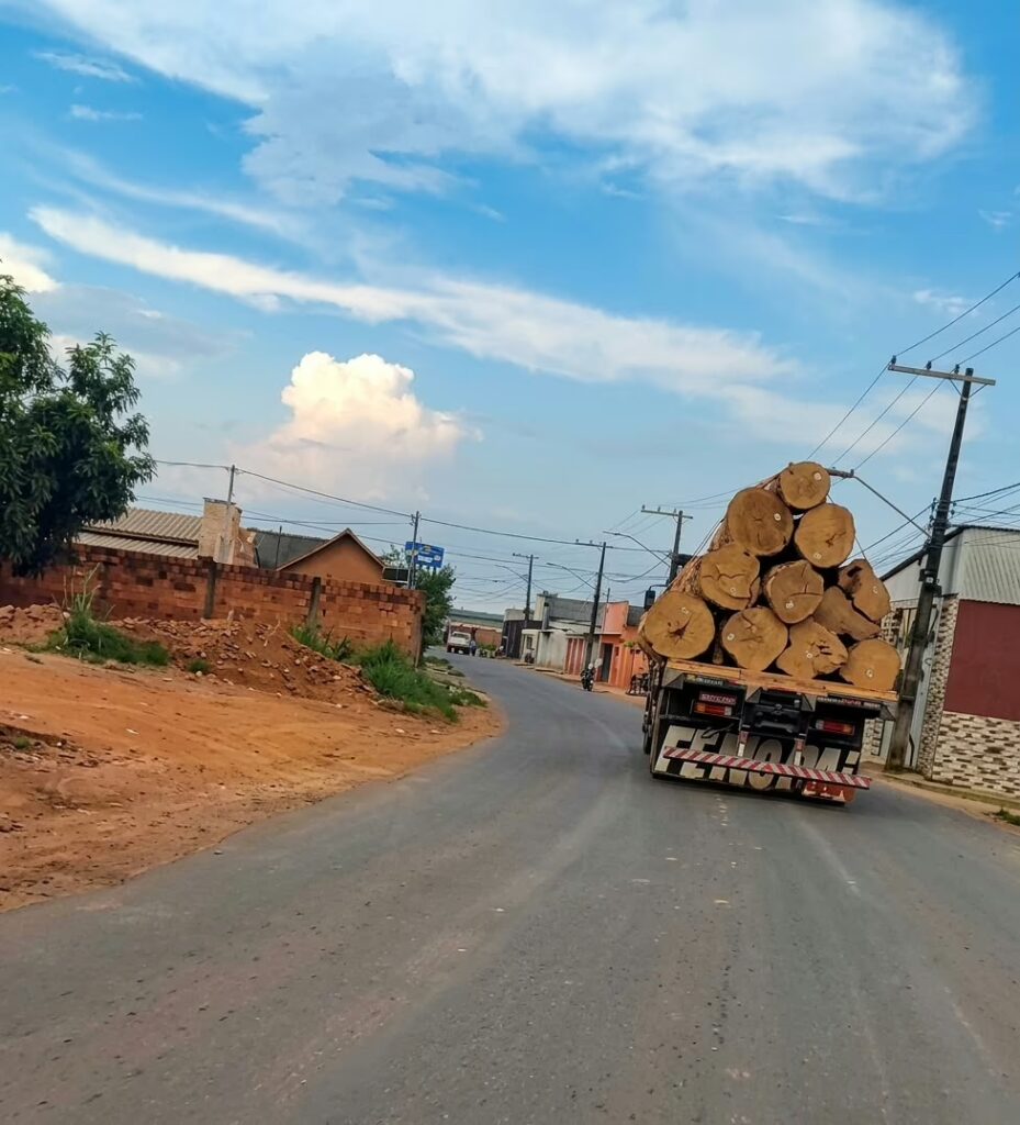 Caminhão com toras circula em rua recém-pavimentada de Sena Madureira.
