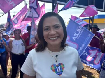 Candidata Mailza Assis sorri acompanhada de militantes com bandeiras de campanha em Rio Branco.