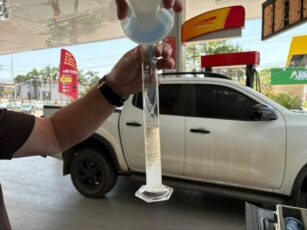 Fiscal do Procon do Acre inspecionando bomba de combustível e documentação em posto de gasolina.
